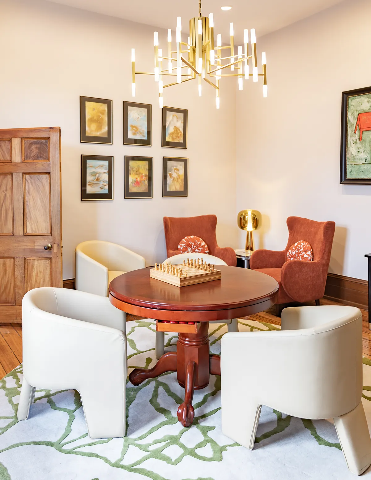 A drawing room with a brass chandelier, framed art and a chess table